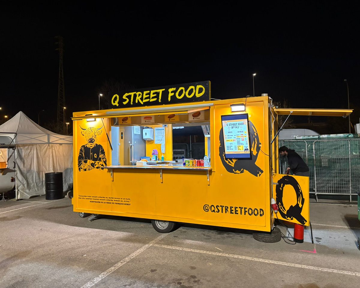 Food truck amarillo de Q Street Food preparado para un evento nocturno