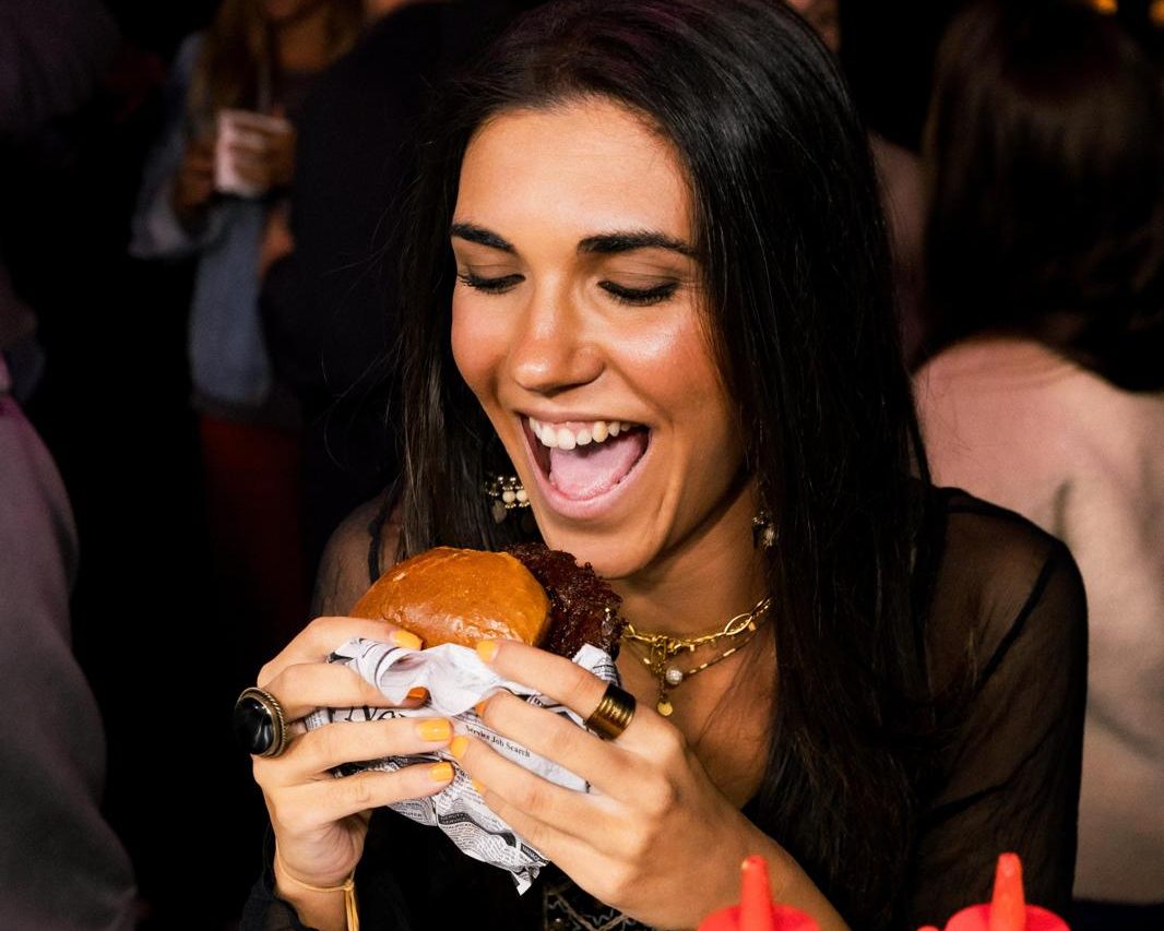 Clienta disfrutando de una hamburguesa de Q Street Food en un evento